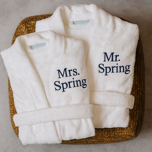 White bathrobes with 'Mr. Spring' and 'Mrs. Spring' text on a woven basket.