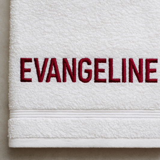 White towel with 'EVANGELINE' embroidered in red on a neutral background
