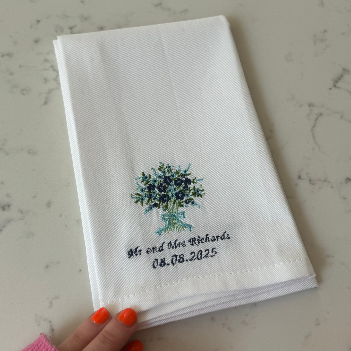 Handkerchief with embroidered design and text on a marble surface