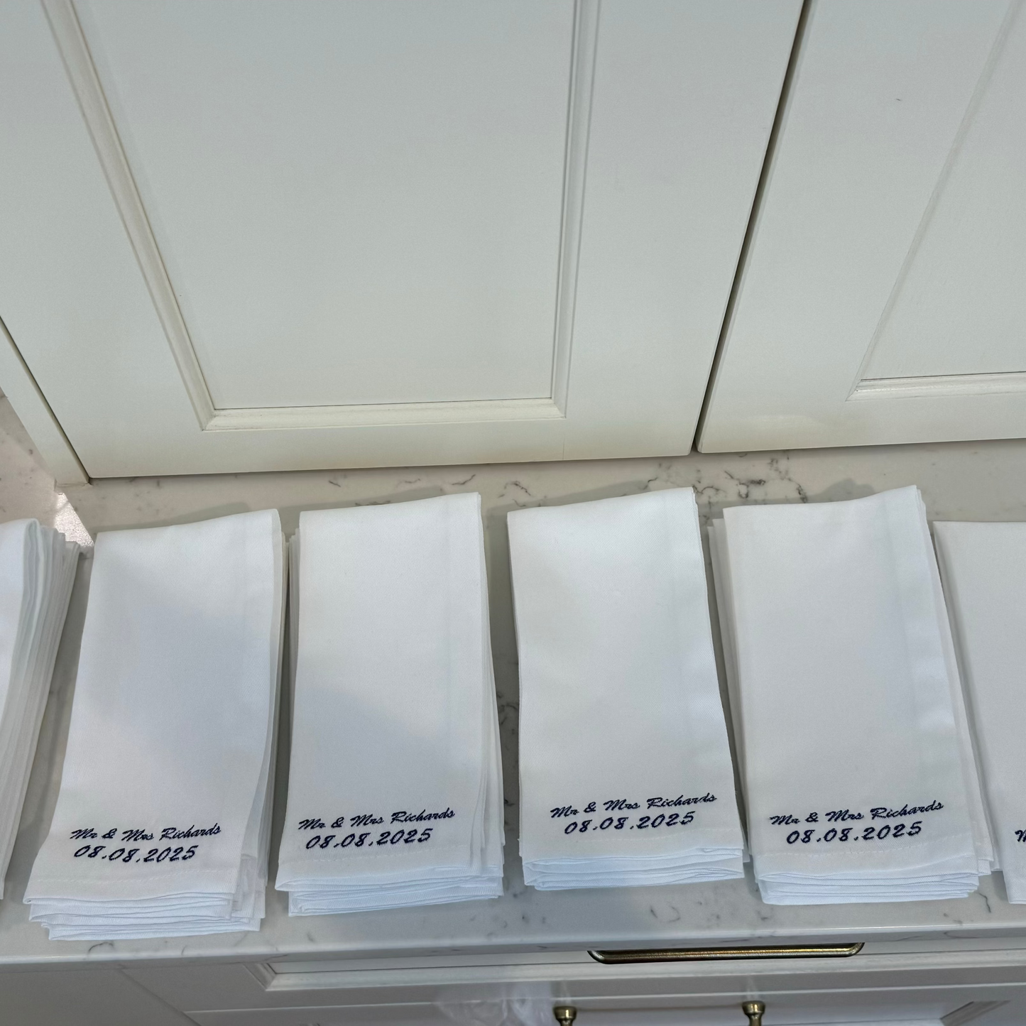 White napkins with black text on a white surface next to a cabinet.