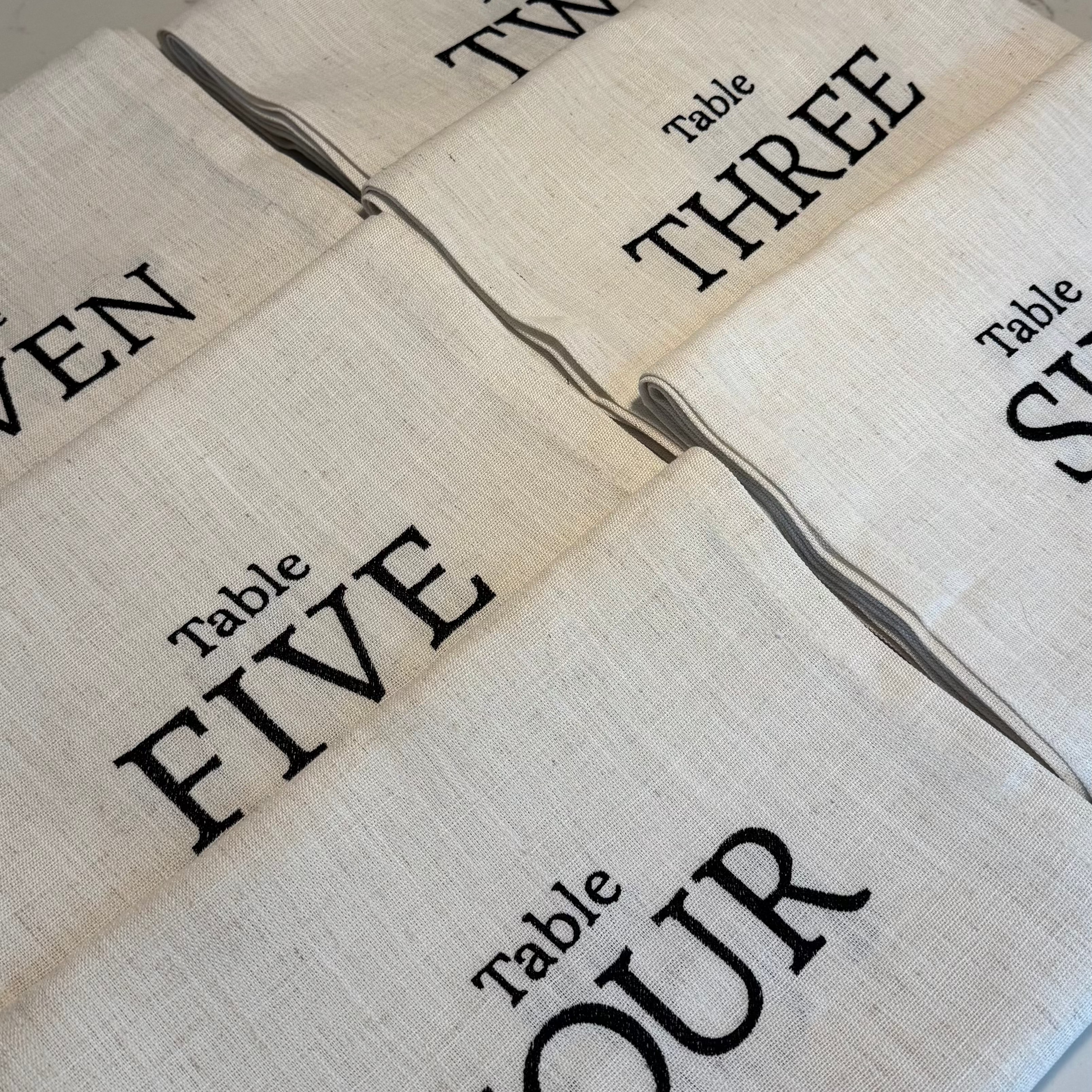 Set of beige table runners with black text indicating table numbers.
