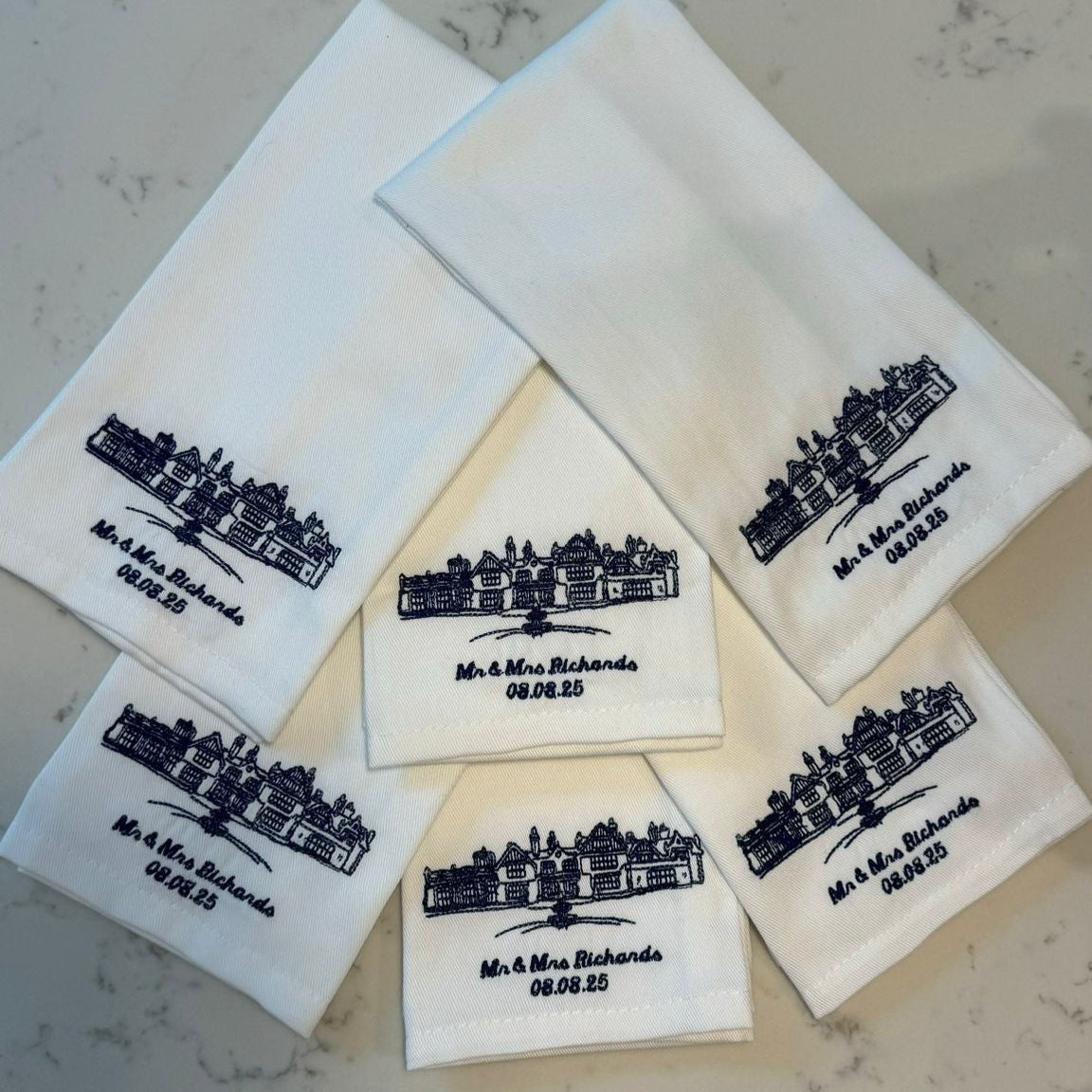 Set of white napkins with black text and logo on a gray surface